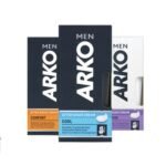 Product Image (Tube): "A 1.7 oz tube of Arko After Shave Cream with blue and white packaging, standing upright on a clean countertop." Texture Close-up: "A dab of smooth, white after shave cream on the tip of a finger against a neutral background." Lifestyle Shot (Application): "A man gently applying after shave cream to his cheeks while looking in a mirror." Flat Lay with Razor: "Arko After Shave Cream tube placed next to a shaving razor and towel on a bathroom surface."