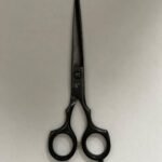 7-inch-professional-barber-scissors-stainless-steel-razor-edge.jpg  "Close-up of professional 7-inch barber scissors with silver stainless steel blades and an ergonomic offset handle."  barber-using-7-inch-shears-for-scissor-over-comb.jpg "Professional barber performing a scissor-over-comb technique using 7-inch hair cutting shears."  razor-edge-hollow-ground-blade-detail.jpg "Macro shot of the hand-honed razor edge on high-carbon steel barber scissors."