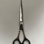 7-inch-professional-barber-scissors-stainless-steel-razor-edge.jpg  "Close-up of professional 7-inch barber scissors with silver stainless steel blades and an ergonomic offset handle."  barber-using-7-inch-shears-for-scissor-over-comb.jpg "Professional barber performing a scissor-over-comb technique using 7-inch hair cutting shears."  razor-edge-hollow-ground-blade-detail.jpg "Macro shot of the hand-honed razor edge on high-carbon steel barber scissors."