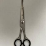 7-inch-professional-barber-scissors-stainless-steel-razor-edge.jpg  "Close-up of professional 7-inch barber scissors with silver stainless steel blades and an ergonomic offset handle."  barber-using-7-inch-shears-for-scissor-over-comb.jpg "Professional barber performing a scissor-over-comb technique using 7-inch hair cutting shears."  razor-edge-hollow-ground-blade-detail.jpg "Macro shot of the hand-honed razor edge on high-carbon steel barber scissors."
