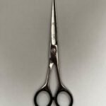 7-inch-professional-barber-scissors-stainless-steel-razor-edge.jpg  "Close-up of professional 7-inch barber scissors with silver stainless steel blades and an ergonomic offset handle."  barber-using-7-inch-shears-for-scissor-over-comb.jpg "Professional barber performing a scissor-over-comb technique using 7-inch hair cutting shears."  razor-edge-hollow-ground-blade-detail.jpg "Macro shot of the hand-honed razor edge on high-carbon steel barber scissors."