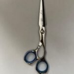 7-inch-professional-barber-scissors-stainless-steel-razor-edge.jpg  "Close-up of professional 7-inch barber scissors with silver stainless steel blades and an ergonomic offset handle."  barber-using-7-inch-shears-for-scissor-over-comb.jpg "Professional barber performing a scissor-over-comb technique using 7-inch hair cutting shears."  razor-edge-hollow-ground-blade-detail.jpg "Macro shot of the hand-honed razor edge on high-carbon steel barber scissors."