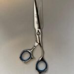7-inch-professional-barber-scissors-stainless-steel-razor-edge.jpg  "Close-up of professional 7-inch barber scissors with silver stainless steel blades and an ergonomic offset handle."  barber-using-7-inch-shears-for-scissor-over-comb.jpg "Professional barber performing a scissor-over-comb technique using 7-inch hair cutting shears."  razor-edge-hollow-ground-blade-detail.jpg "Macro shot of the hand-honed razor edge on high-carbon steel barber scissors."