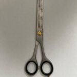 7-inch-professional-barber-scissors-stainless-steel-razor-edge.jpg  "Close-up of professional 7-inch barber scissors with silver stainless steel blades and an ergonomic offset handle."  barber-using-7-inch-shears-for-scissor-over-comb.jpg "Professional barber performing a scissor-over-comb technique using 7-inch hair cutting shears."  razor-edge-hollow-ground-blade-detail.jpg "Macro shot of the hand-honed razor edge on high-carbon steel barber scissors."