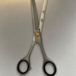 7-inch-professional-barber-scissors-stainless-steel-razor-edge.jpg  "Close-up of professional 7-inch barber scissors with silver stainless steel blades and an ergonomic offset handle."  barber-using-7-inch-shears-for-scissor-over-comb.jpg "Professional barber performing a scissor-over-comb technique using 7-inch hair cutting shears."  razor-edge-hollow-ground-blade-detail.jpg "Macro shot of the hand-honed razor edge on high-carbon steel barber scissors."