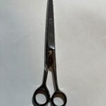7-inch-professional-barber-scissors-stainless-steel-razor-edge.jpg  "Close-up of professional 7-inch barber scissors with silver stainless steel blades and an ergonomic offset handle."  barber-using-7-inch-shears-for-scissor-over-comb.jpg "Professional barber performing a scissor-over-comb technique using 7-inch hair cutting shears."  razor-edge-hollow-ground-blade-detail.jpg "Macro shot of the hand-honed razor edge on high-carbon steel barber scissors."